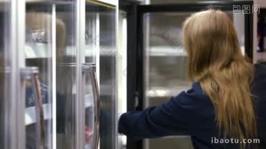 年轻的<strong>女士</strong>在冷冻区打开冰箱，选择并拿走产品